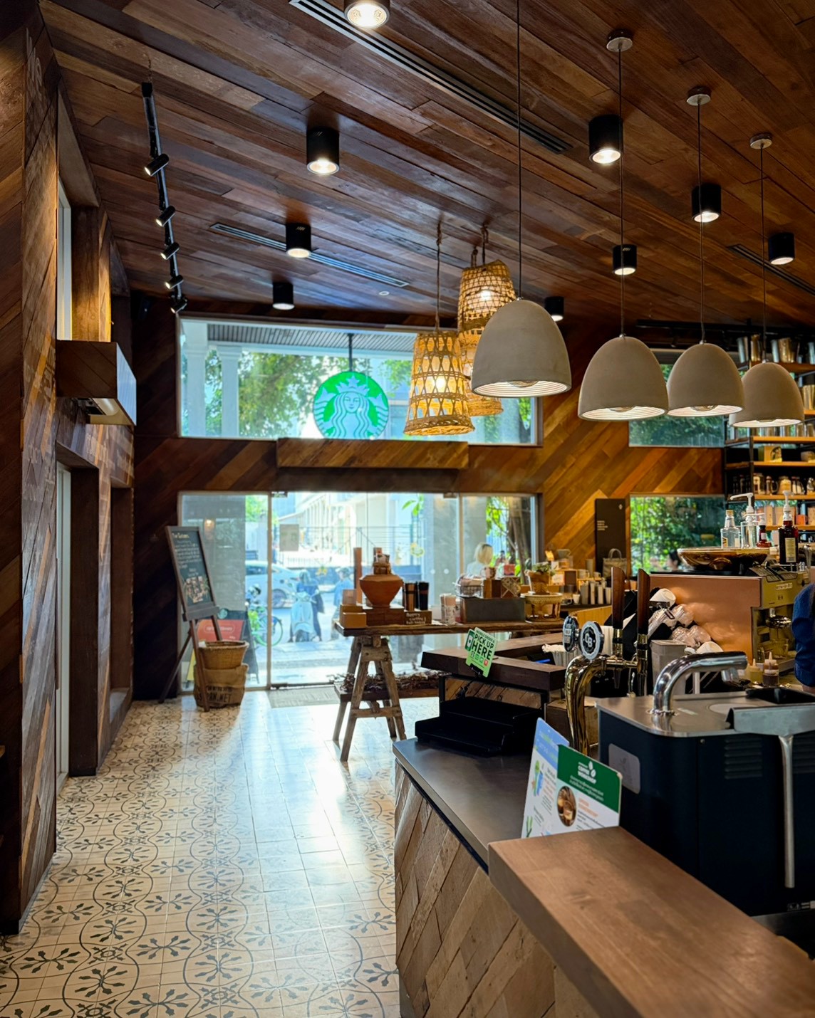 曼谷 Starbucks Langsuan 店內，木質天花、藤編吊燈與花磚地坪